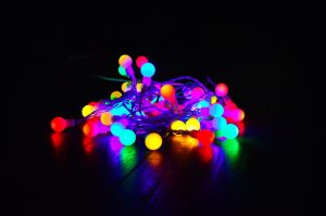 A bundle of colorful string lights glowing warmly in a dark indoor setting.