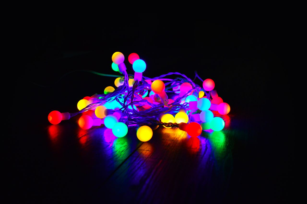A bundle of colorful string lights glowing warmly in a dark indoor setting.